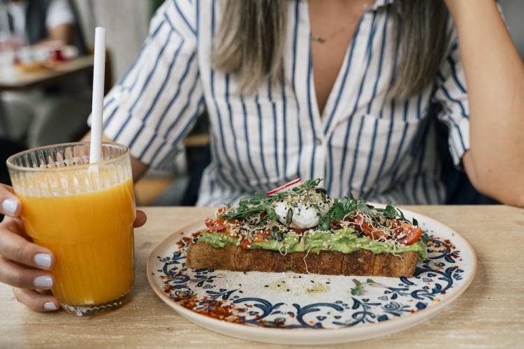 girl at cafe with orange juice and fancy avocado toast